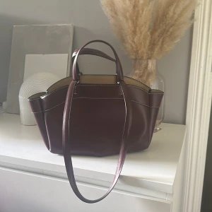 Vinröd handväska i skinn med axelrem - Svin snygg väska från Zara i vin röd , säljer då jag aldrig använder den! Köptes i våras som ny använd 2-3 ggr😇💕