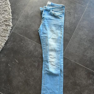 Ljusblå skinny jeans från Jack & Jones - Säljer ett par ljusblå skinny jeans från Jack & Jones med klassisk femficksdesign och snygga slitningar framtill. Jeansen har normal passform i midjan och är tillverkade i mjukt jeansmaterial med stretch för extra komfort. Perfekt för dig som gillar en smal siluett och ljusa toner.