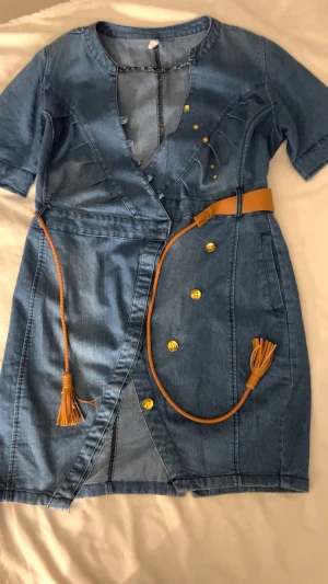 Jeansjacka med bälte och guldknappar  - Snygg jeansjacka från Mexx i storlek XL (d går o ha om man är s/M som jag om man gillar oversized) med korta ärmar,  guldiga knappar och täcker nästan ner till låren. Jackan har ett brunt bälte som ger en cool touch(går att ta bort). Perfekt för dig som gillar denim och vill sticka ut med detaljer.