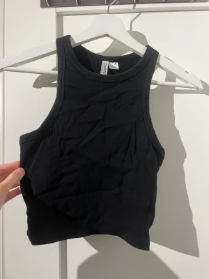 Svart ribbad linnetopp H&M Divided - Svart ribbad linnetopp från H&M Divided. Modellen är ärmlös med hög halsringning och croppad passform.  Använd fåtal gånger!