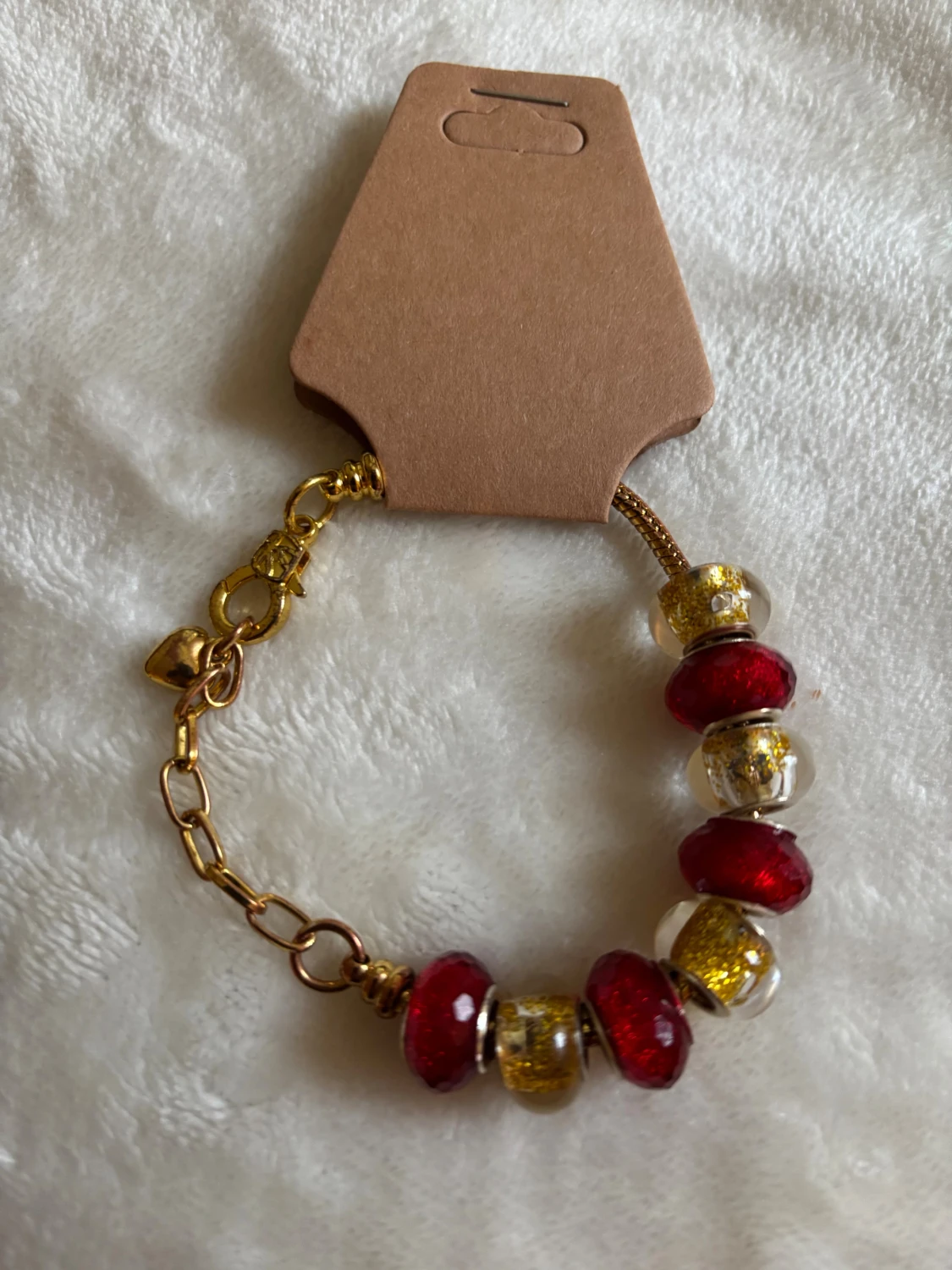 Guldarmband med röda och glittriga pärlor