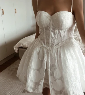 Supersöt studentklänning/festklänning!  - Supersöt vit kort klänning med tunna axelband och en korsettliknande överdel som markerar midjan. Den utsvängd och av styvt material, så formen bibehålls. Använd 2 gånger, inga defekter. 