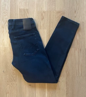 Mörkblå Replay Anbass jeans W29 L30 - Jag säljer dom här riktigt snygga Replay Anbass jeansen som är i storlek W29 L30. Dom är som nya och har inga skador och defekter. Tveka inte att höra av er!                                                          Mått: Längd=99cm. Midja=38cm