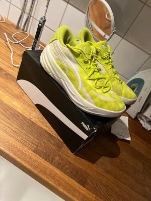 Puma All-Pro Nitro sneakers gul/ lime grön - Säljer ett par Puma All-Pro Nitro sneakers i en riktigt fräsch gul färg med vita detaljer. Skorna har en sportig och modern design med snörning och platt sula. Ovandelen är i syntetmaterial och mesh för bra ventilation. Perfekt för dig som gillar att sticka ut med dina skor. De är ett par väldigt sköna och bra skor för dig som tränar. Kvitto finns.