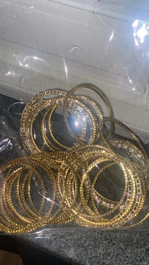 Guldiga armband i set - Säljer ett set med flera tunna armband i guldig metall. Armbanden är runda och har ett detaljerat mönster som ger en glittrig och trendig look. Perfekta att mixa och matcha för en snygg layering-effekt.