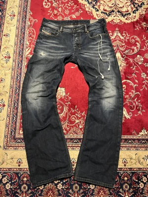 Vintage Diesel bootcut jeans med sjuk fade, W31 L32 - Säljer dessa snygga jeans från Diesel. De har en unik sjukt snygg tvätt och även coola slitningar på båda låren. De ser lite gråaktiga ut på bilden men de är mörkblåa. Passformen är Zatiny, alltså regular bootcut. W31 L32.  Mått: Ytterbenslängd - ca 105 cm Midja - ca 40 cm Benöppning - ca 23 cm Hör av er vid frågor 🙌 Jag kan skicka fler bilder, fråga bara!