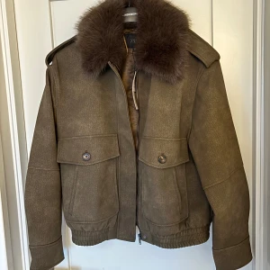 Zara mockaliknande jacka med pälskrage - Så cool meotine liknande Zara jacka/ kort kappa/ bomberjacka i skinn / mockaimitation med avtagbar pälskrage🫶 endast testad aldrig använd, lapparna sitter kvar.  Knäppning med dragkedja och dolda knappar framtill.  Stl S, slutsåld på hemsidan 🩷