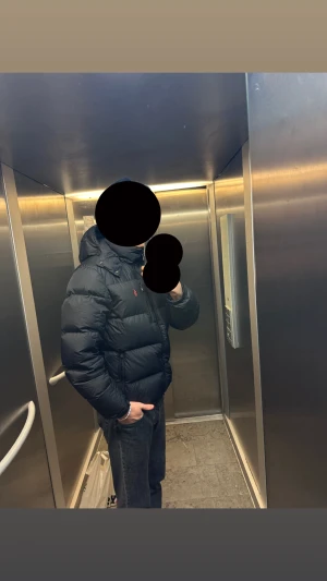 Svart pufferjacka Polo Ralph Lauren M - Säljer en svart pufferjacka från Polo Ralph Lauren i storlek M. Jackan har huva, dragkedja framtill och den klassiska röda Polo-loggan på bröstet. Perfekt för kalla dagar och riktigt skön att bära. Materialet är syntet och dun för extra värme. Priset kan diskuteras vid snabb affär!