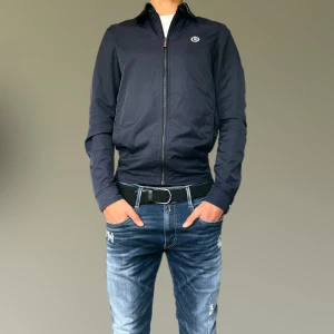 Henri Lloyd jacka - Snygg mörkblå jacka från Henri Lloyd. Jackan är i gott skick, endast några repor på knapparna som syns vid noggrann inspektion. Pris ej hugget i sten. Hör av er vid frågor!