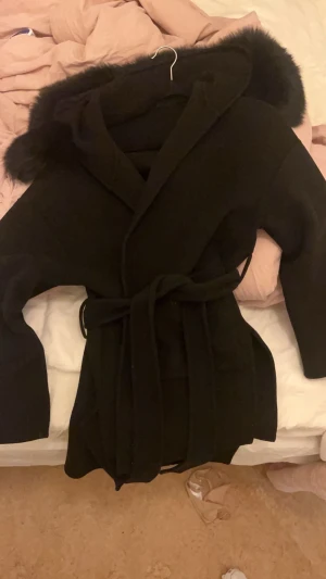 Svart kappa med päls krage  - Säljer nu min favorit ur garderoben💕en svart kort kappa med avtagbar päls på luvan, storlek xs. Fått i present förra året och kommer inte till användning nu längre. Det saknas en knapp på luvan för att fästa pälsen därav priset. men det går lätt att sy dit en ny, pälsen har hållt sig på plats endå🤍