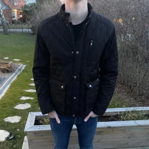 Svart quiltad jacka  - Säljer en svart quiltad jacka med både dragkedja och knappar framtill, perfekt till hösten/vintern. Jackan är från Selected Homme och är i storlek M! Modellen är 182 cm lång. Hör av dig vid minsta fundering! 😀 .