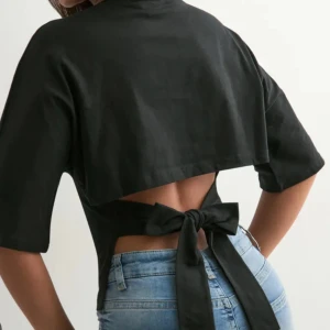 Svart topp med knyt i ryggen - Snygg svart bolerotopp ifrån Nelly med öppen rygg och breda knytband som ger en cool detalj. Toppen har korta ärmar och croppad passform, perfekt att styla med höga jeans. Materialet känns mjukt och lätt mot huden.