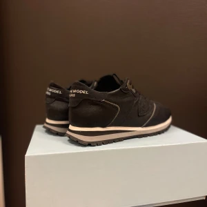 Philippe Model - Snygga svarta sneakers från Philippe Model Paris med klassisk design och rund tå. Skorna har snörning, platt sula och är tillverkade i skinn med detaljer i beige. Perfekta för dig som gillar stilrena och exklusiva sneakers med en urban vibe.