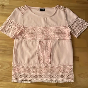 Ljusrosa blus med fina detaljer från Vila, perfekt till en vardag och fest Storlek xs❣️ - Supersöt ljusrosa blus från Vila i storlek XS. Blusen har korta ärmar och är dekorerad med spetspartier både fram och bak vilket ger en extra touch. Perfekt för dig som gillar romantisk stil! 