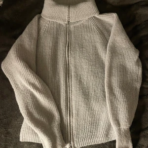 Ljusgrå stickad kofta med dragkedja - Mysig ljusgrå stickad kofta med hög krage och hel dragkedja framtill. Säljer då för det inte kommer till användning 💕