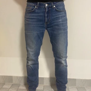 Blå jeans från Arket med stretch - Säljer ett par klassiska blå jeans från Arket med snygg tvätt och komfortstretch. Modellen har fem fickor, raka ben och normal passform. Jeansen är tillverkade i bomull med lite stretch för extra bekvämlighet. Perfekta för en avslappnad och stilren look.