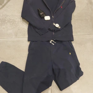 Mörkblå mjukisbyxor Polo Ralph Lauren  - Mörkblå mjukisbyxor från Polo Ralph Lauren i storlek XL. Byxorna har dragsko i midjan, sidofickor och den klassiska gula Polo-loggan broderad på benet. Tillverkade i mjukt bomullsmaterial för maximal komfort.