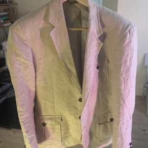 Beige linnekavaj från Celtic Tweed - Snygg beige kavaj från Celtic Tweed i linne med klassisk krage och två framfickor med knappar. Insidan har ett coolt kartmönstrat foder i satin. Org pris runt 3200 o är i princip oanvänd 