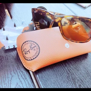 Ray-Ban Wayfarer solglasögon brun uv skydd 3  - Säljer ett par Ray-Ban Wayfarer solglasögon med brunmelerad båge och klassisk form. Glasen är tonade och ger snygg look. Kommer med originalfodral i ljusbrunt skinn. Perfekt för dig som vill ha stil och kvalitet. Uv skydd 3