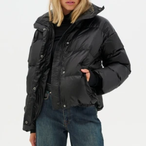 Svart pufferjacka med hög krage - Snygg svart pufferjacka med hög krage. Används fåtal gånger och köptes förra året. Nypris är 3000, men säljer för 1200. Kan tänka mig att gå ned i pris vid snabb affär