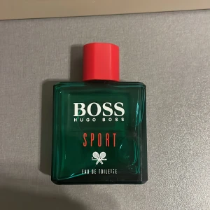Hugo Boss Sport Eau de Toilette - Fräsch och energisk Eau de Toilette från Hugo Boss. Perfekt för dig med aktiv livsstil som vill ha en modern och sportig touch. Snygg design med röd kork och tennisdetalj på flaskan. Kan gå ner i pris vid snabb affär 