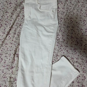 Vita jeansbyxor från Pieces  - Snygga vita jeansbyxor från Pieces i storlek S. Klassisk femficksmodell med dragkedja och knapp framtill. Byxorna har rak passform och är tillverkade i mjukt bomullsmaterial med lite stretch för extra komfort. Perfekt för dig som gillar stilrena och fräscha looks.