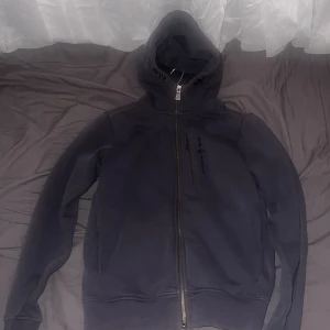 Svart hoodie från Sail Racing XS - Mörkgrå hoodie från Sail Racing i storlek XS. Tröjan har hel dragkedja framtill och med huva