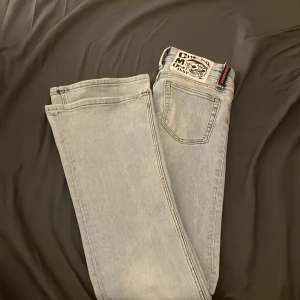 Ljusblå Cheap Monday jeans bootcut - Säljer ett par ljusblåa jeans från Cheap Monday med bootcut-snitt och låg midja. Jeansen har klassisk femficksdesign, dragkedja och knapp framtill samt en snygg logotyp på bakfickan. 