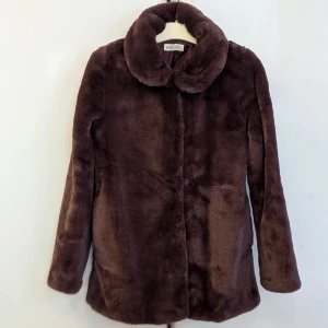 Burgundy / mörk lila fuskpälsjacka från H&M - FUSKPÄLSJACKA ANVÄND EN ENDA GÅNG. Säljer en fluffig och mjuk burgundy / mörk lila fuskpälsjacka från H&M i storlek 164. Jackan har en bred krage, långa ärmar och stängs med knappar framtill. Perfekt för dig som vill ha en cozy och stylish look under kyliga dagar. Jätte bra skick på jackan.