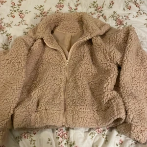 Beige teddyjacka från SHEIN - Mysig teddyjacka i beige från SHEIN, storlek S. Jackan har fluffig yta, dragkedja framtill och är helfodrad. Perfekt för kyliga dagar och har en chill, oversized vibe. Materialet är 100% polyester och jackan har långa ärmar.Tycker färgen går mot aprikos.