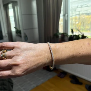 Caroline Svedbom Guldarmband med glittrande stenar - Ett elegant och smalt armband i guld med en rad glittrande stenar runt hela bandet. Perfekt för dig som gillar stilrena och lyxiga smycken som ändå känns diskreta. Armbandet har en klassisk design som aldrig går ur tiden.