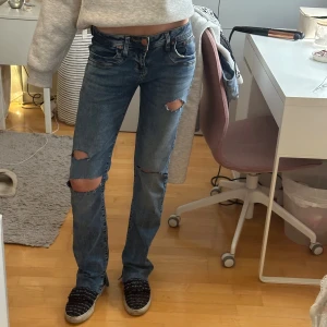 Blå bootcut jeans med slitningar - Midjemått: 34cm tvärsöver, innerbensläng: 80cm, gjort slitningarna själv samt klippt upp och klippt slits
