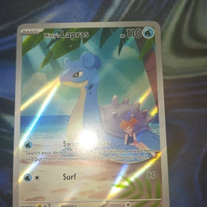 Misty's Lapras - Coolt Pokémonkort med Misty och Lapras vid stranden! Perfekt för samlare och fans av Pokémon. Kortet har snygg design och passar både till spel och som samlarobjekt. Ett måste för dig som gillar äventyr och nostalgi!