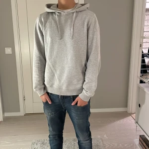 Grå hoodie från Stenströms - Snygg ljusgrå hoodie från Stenströms. Tröjan har huva med snörning och är tillverkad i mjuk bomull. Perfekt för chill dagar och enkel att matcha med jeans eller joggers. Skick 9/10 nypris ligger runt 2600kr