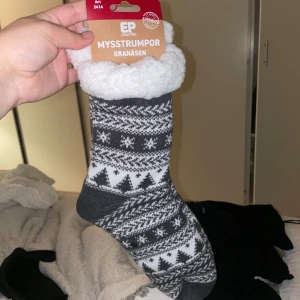 Mysstrumpor - Supergosiga mysstrumpor från EP Collection Granåsen med fluffig vit insida och grått/vitt vintermönster. Perfekta för kalla dagar, med snyggt mönster av granar och snöflingor. Strumporna är tjocka och har en mjuk frottéliknande insida för extra värme.