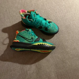 Turkosa Nike sneakers med färgglada detaljer - Säljer ett par unika Nike sneakers i turkos mesh med svarta detaljer och snörning. Skorna har färgglada mönster i gult, rött och orange på häl och sula, samt svart sula med coolt mönster. Perfekta för dig som vill sticka ut med din stil.