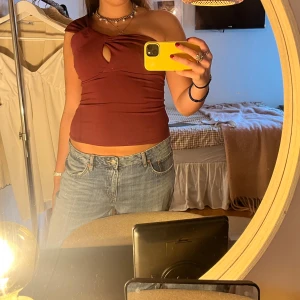 Vinröd oneshoulder topp med cut-out - Säljer en vinröd topp med oneshoulder-design och snygg cut-out detalj framtill. Toppen är tight och har en cool twistad effekt vid axeln❣️❣️❣️