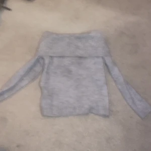 Grå offshoulder stickad tröja Gina Tricot - Superfin ljusgrå stickad tröja från Gina Tricot med bred ribbad offshoulder-krage. Aldrig använt! Storleken är ungefär som S. 