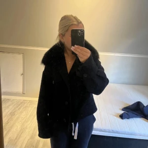 Svart jacka från Meotine - Snygg svart jacka från Meotine med en lyxig pälsdetalj på kragen. Jackan har en croppad passform och knappar framtill. Den är inte alls myller använd. Skriv för fler bilder!💓
