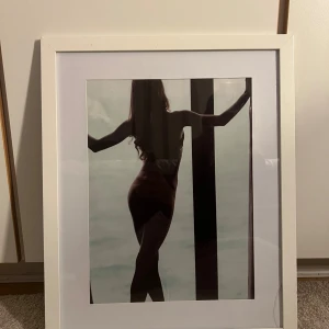 Tavla  - En tavla av en siluett av en kvinna vid ett fönster. Perfekt som modern väggkonst för att ge ditt rum en stilren och mystisk känsla. Passar dig som gillar minimalistisk och konstnärlig inredning.