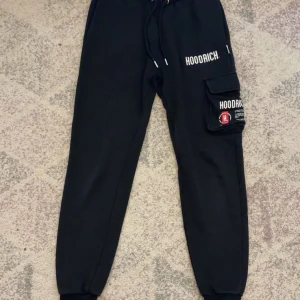 Svarta Hoodrich cargopants XS - Snygga och bekväma Hoodrich mjukisbyxor i storlek XS. Fint skick, bara använt några gånger. Svarta med logga på benet och ficka på sidan. Passar både killar och tjejer.