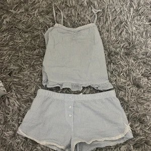 Blåvit pyjamas bomullsshorts och topp med spets -  blåvit randiga shorts och topp. Shortsen har  knappar framtill och spetsdetaljer längs bensluten. Toppen har vita spetsdetaljer.