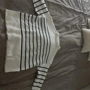 Vit och svart randig stickad tröja - Säljer en vit stickad tröja med svarta horisontella ränder. Tröjan har bred ribbad mudd nertill och vid ärmsluten. Perfekt för dig som gillar en stilren och tidlös look. Det är strl Xs. använd fåtal gånger så nästan ny.Hör av er vid funderingar😊💕