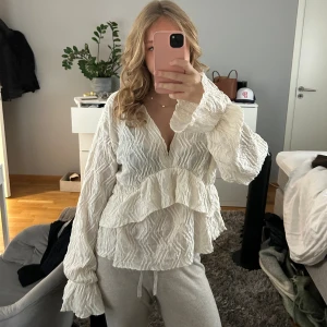 Vit blus med volanger och struktur - Säljer en beige blus med volangdetaljer både framtill och baktill i storlek XL men passar även L och M, de bror på hur man vill att den ska sitta. Den är från Gina tricot i jättebra skick😊