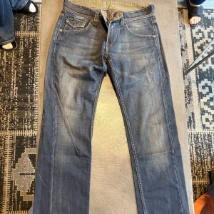 Blå jeans från Rag Style - Snygga blå jeans från Rag Style med coola detaljer som mönstrad insida och unika bakfickor med broderade vågformer. Klassisk femficksmodell och slitningar som ger en avslappnad vibe. Passar dig som gillar street och personlig stil.