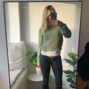 Grön stickad tröja från KappAhl - Mysig grön stickad tröja från KappAhl med rund halsringning och ribbade muddar. Modellen är croppad och har en relaxed fit med långa ärmar. Perfekt för lager-på-lager och chill dagar. Passar både Xs och S (jag är S)