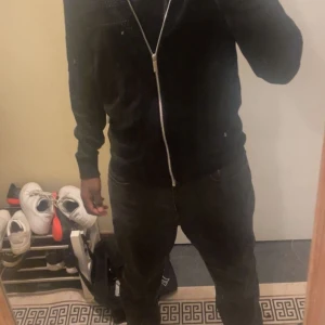 Svart cardigan med dragkedja - Säljer en svart cardigan med hel dragkedja framtill. Jackan har en klassisk, stilren look med långärmade ärmar och ribbade muddar. Perfekt för dig som gillar enkel och snygg streetstil. Passformen är normal och jackan är gjord i ett syntetmaterial.