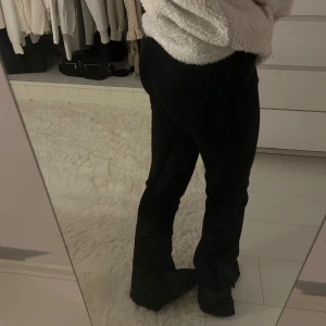 Svarta bootcut jeans med slits - Säljer ett par svarta jeans med bootcut passform och snygga slitsar vid bensluten. klassisk femficksdesign med knapp och dragkedja framtill. Stretchiga i tyget och inte jeans material utan mer mjuka, dom är midwaist. Knappast använda! Storlek 34/36, pris:100kr 