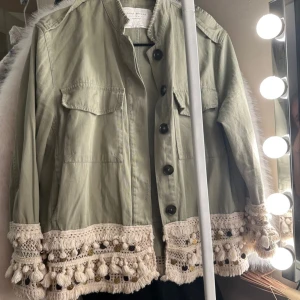 Grön Zara jacka - Snygg ljusgrön jacka från Zara. Jackan har unika virkade detaljer med tofsar och pärlor i beige längs nederkant och ärmslut. Skriv för frågor💗💗.