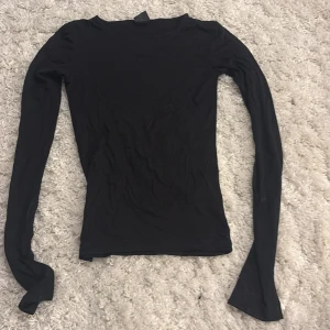 Svart långärmad topp från Gina Tricot - Svart långärmad topp från Gina Tricot i storlek XXS. Modellen är slim och har en enkel, klassisk rund halsringning. Materialet är mjukt och stretchigt, troligtvis bomull eller polyester. Perfekt att styla med jeans eller kjol för en clean look.